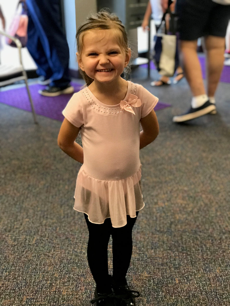 Mia smiling in one of her first dance outfits as a young child